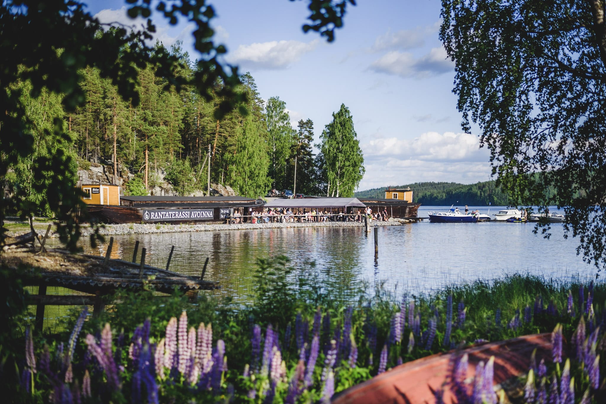 Perinnepihalta otettu kuva järven yli Rantaterassista. Terassi täynnä vieraita